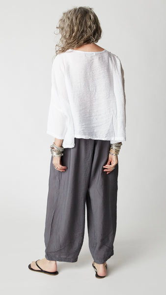 Model wearing gray rayon cropped dart pant, white rayon dropped shoulder cropped top, silver bangles and black flip-flops.