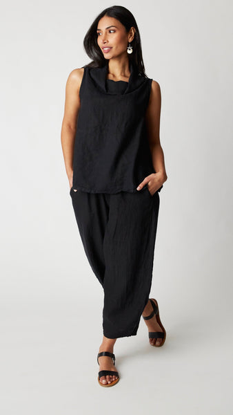 Model wearing black linen ankle length lantern pant with black linen boxy fit sleeveless top, and black leather sandals. 